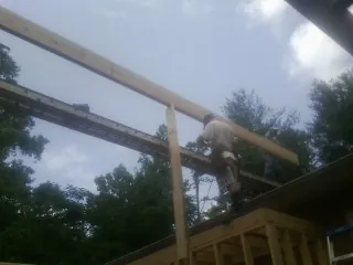 Carpenter setting a ridge beam over a new addition frame in Carrboro