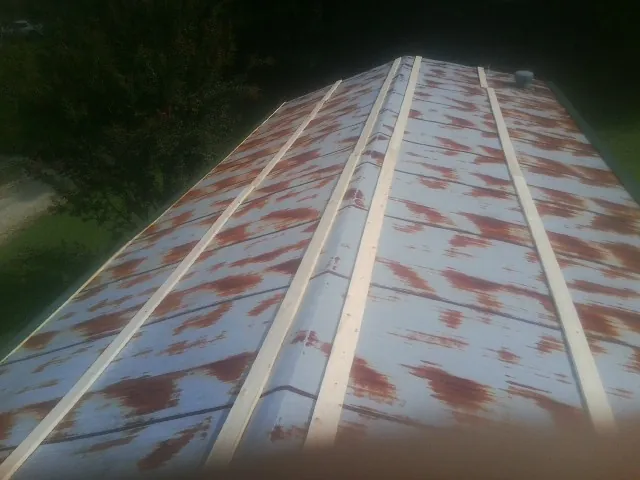 Rusted metal roof panels with new wood purlins before replacement — Storm Damage Roof Repair in Carrboro by Roofing Brothers