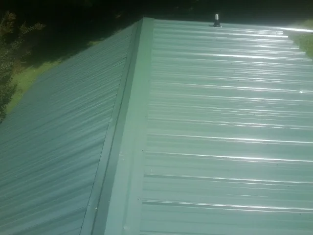 New green metal panels meeting at the ridge of a roof — Flat Roof Repair work by our crew in Carrboro