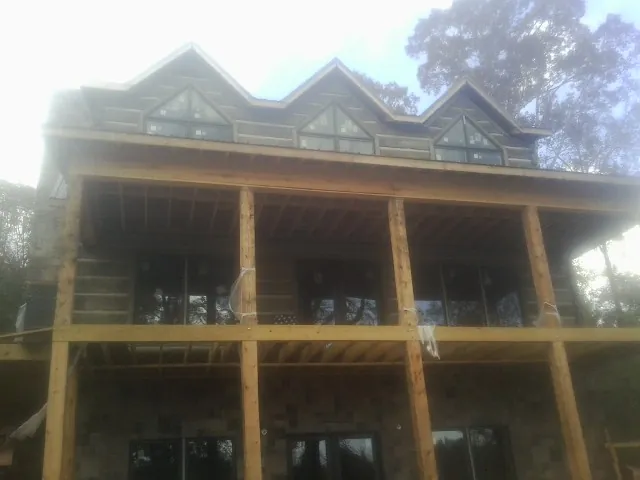 Dormers and porch framing on a large log home under construction — Roof Coating work by our crew in Carrboro