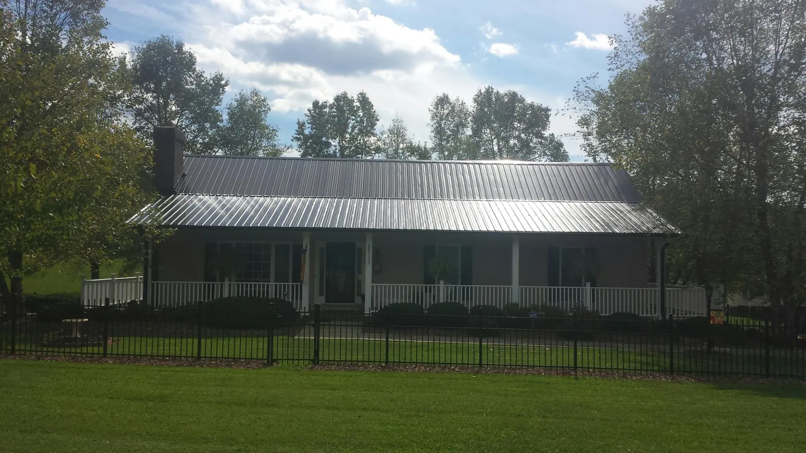 Gray metal roof on a brick ranch with a full width front porch — Gutter Guard Installation work by our crew in Carrboro