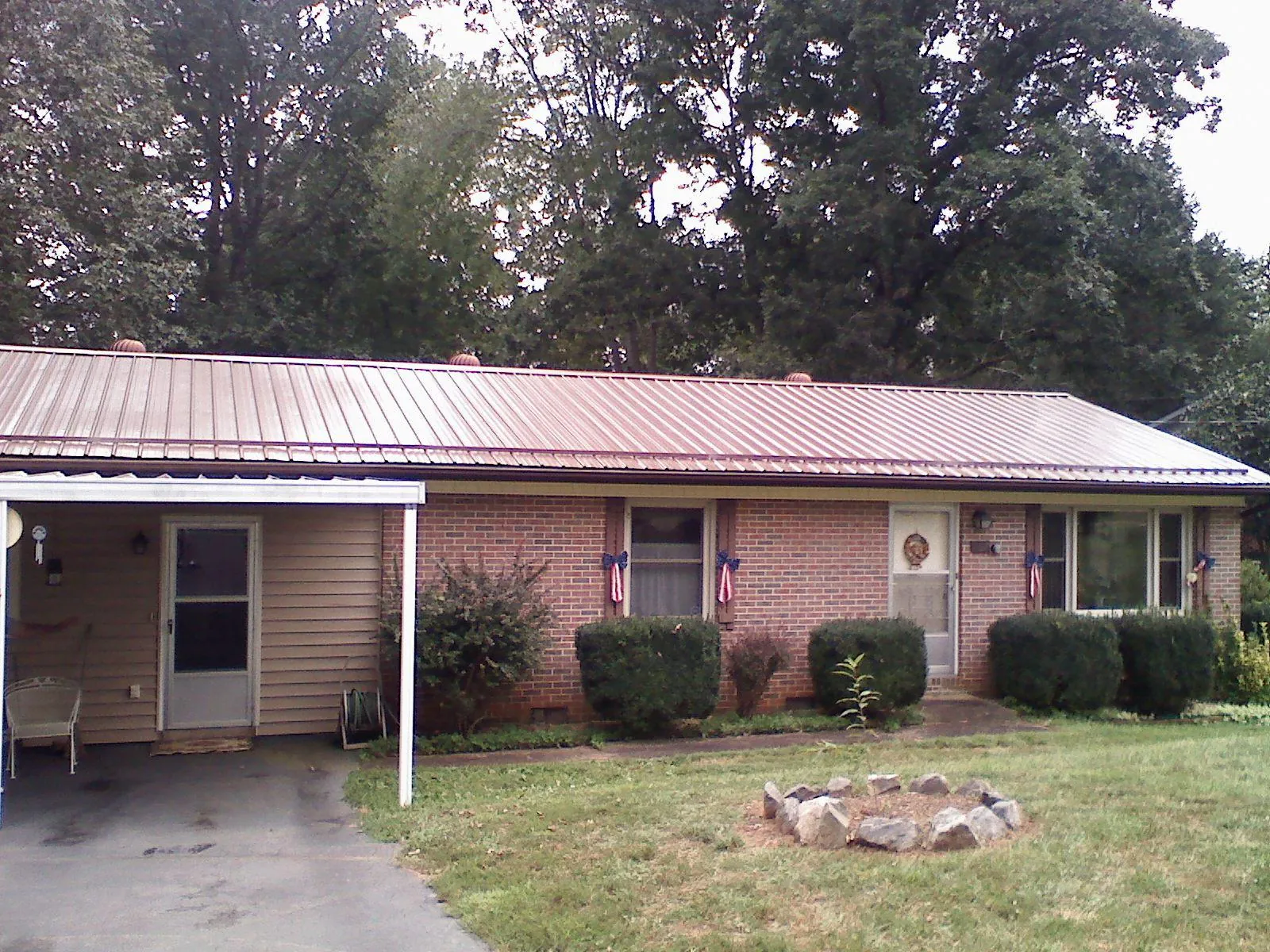 Bronze metal roof and carport on a brick ranch home — Roof Repair work by our crew in Carrboro