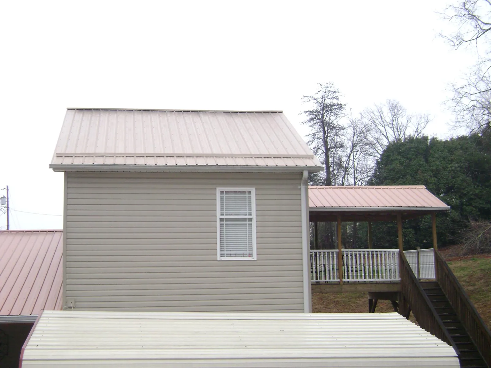 Tan metal roofs on a two story addition and attached porch, from a Roof Replacement job in Carrboro
