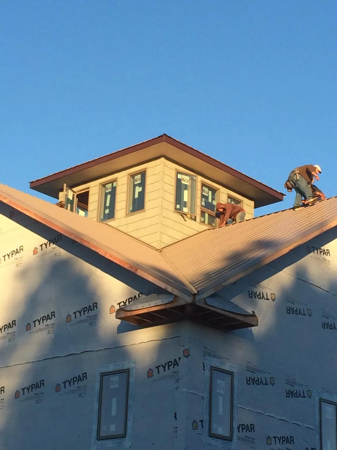 Roofers working around a rooftop cupola on a new metal roof at sunset — Roof Waterproofing in Carrboro by Roofing Brothers